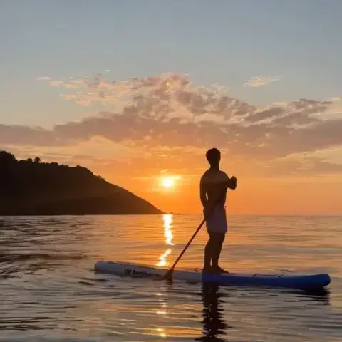 Pratiquant de paddle debout au coucher du soleil