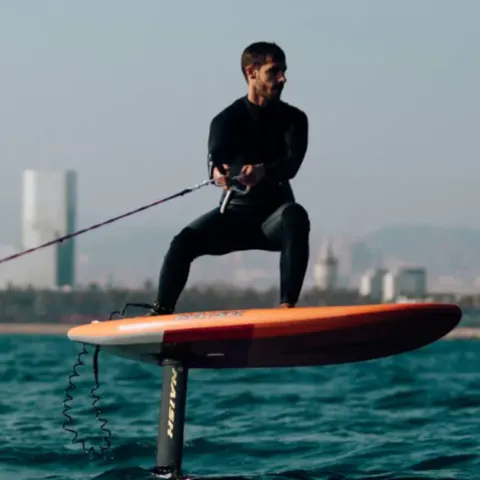 Pratiquant de foil sur l'eau, immeubles à l'horizon
