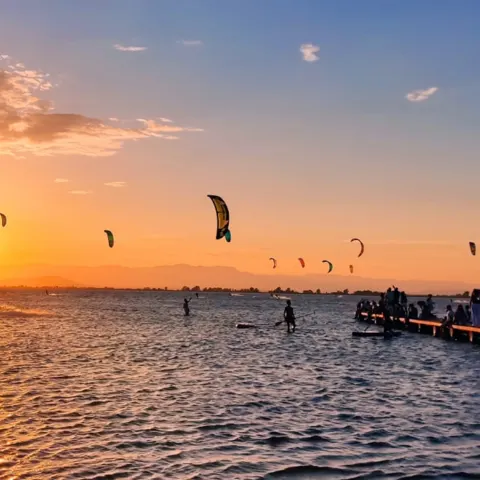 Kitesurfeurs au coucher du soleil, ponton au premier plan