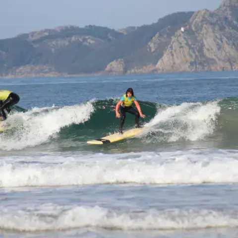 Deux élèves sur une vague, montagne en fond