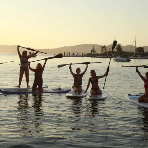 Groupe de paddle au coucher du soleil, bras levés