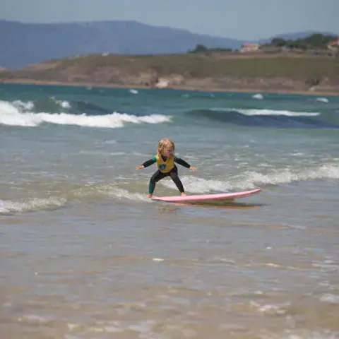 Élève de surf dans les vagues, côte en arrière-plan