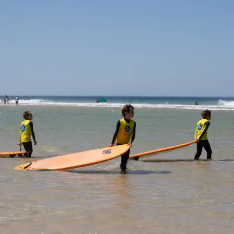 Élèves portant leurs planches vers l'eau