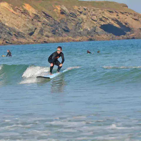 Élève de surf sur une vague, falaise en arrière-plan