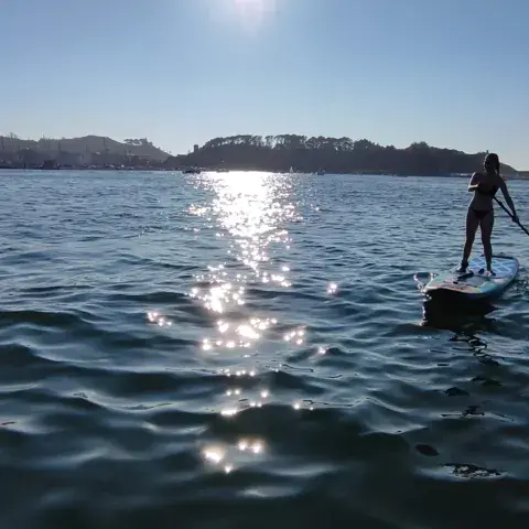 Pagayeuse en stand up paddle face au soleil