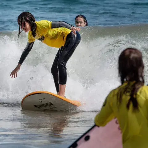 Élève de surf debout sur une planche dans les vagues