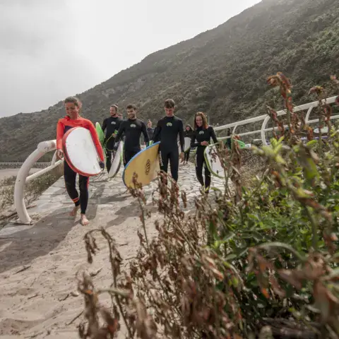 Surfeurs en route vers l'eau avec leurs planches