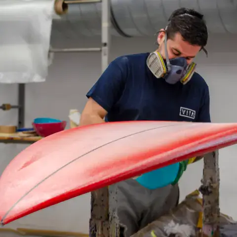 Finition d'une planche rouge à l'atelier