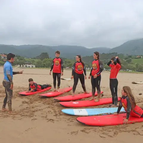 Cours de surf sur la plage de La Espasa, planches rouges alignées