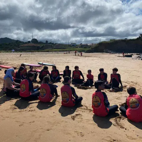 Groupe d'élèves assis en cercle sur le sable pour la théorie