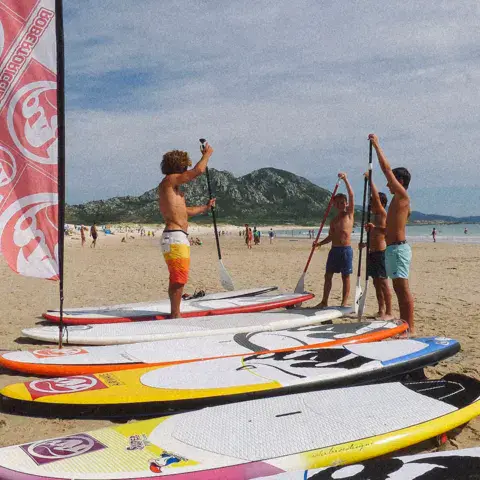 Planches de paddle alignées sur la plage devant le drapeau de l'école