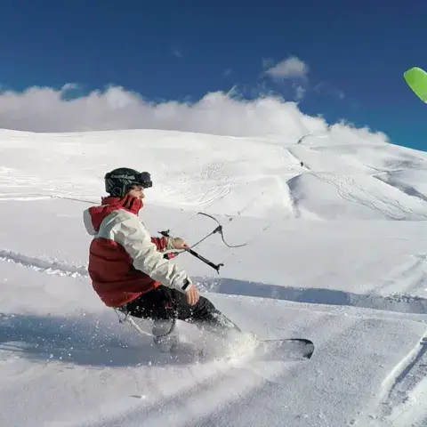 Snowkiter à skis sur la neige avec une aile verte