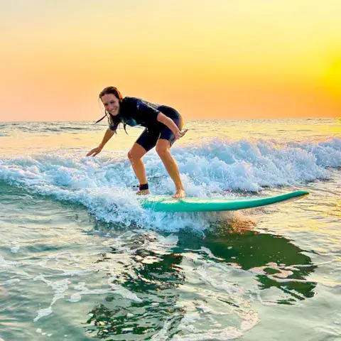Surfeuse sur une vague au coucher du soleil