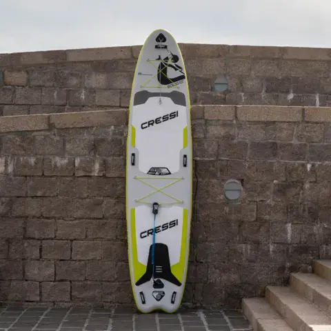 Stand up paddle gonflable devant un mur de pierre