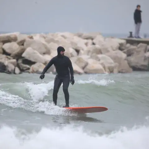 Surfeur en combinaison près d'une digue