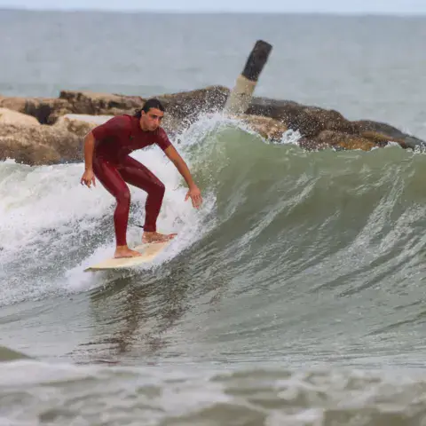 Surfeur sur une vague le long d'une digue