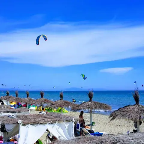 Plage aménagée avec paillotes et kites au large