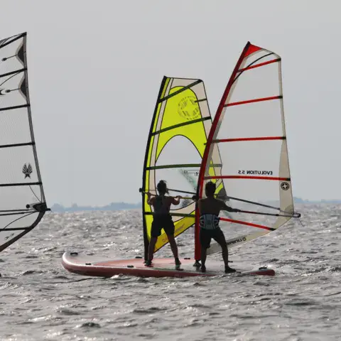 Windsurfeurs en cours dans l'eau peu profonde