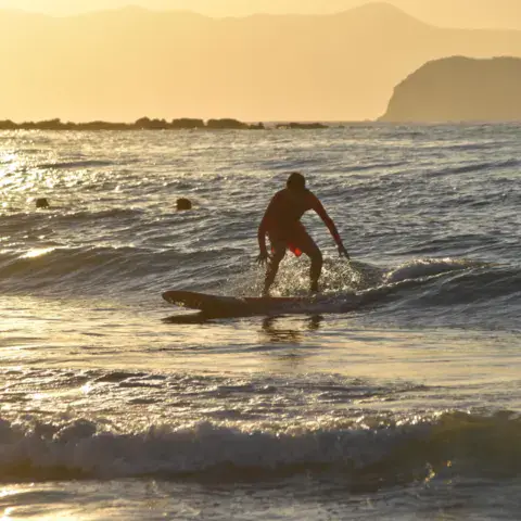 Surfeur sur une vague en lumière dorée