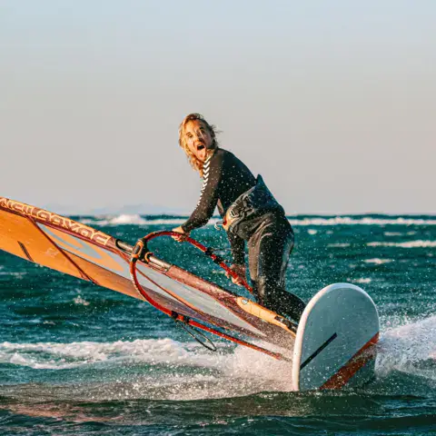 Windsurfeur sur une planche orange en pleine vitesse