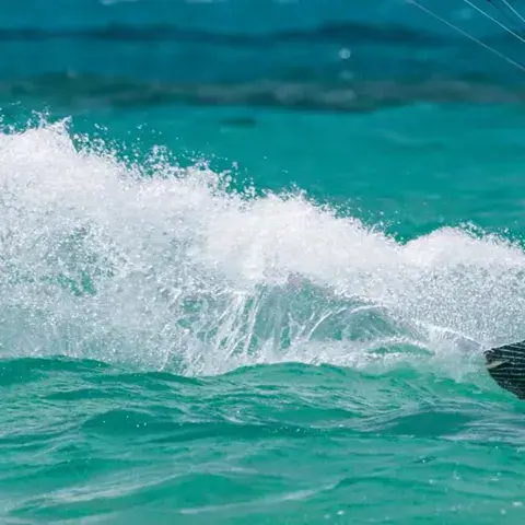 Kitesurfeur en navigation, gerbe d'eau devant la planche