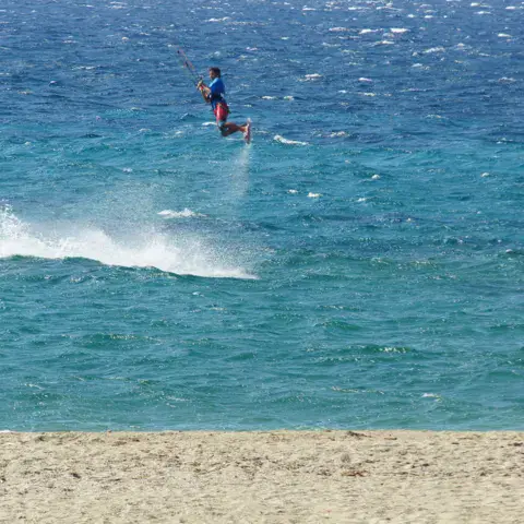 Kitesurfeur dans un saut au large d'une plage de sable