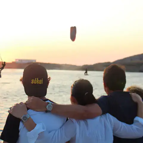 Groupe sur le rivage regardant un kitesurfeur au coucher du soleil