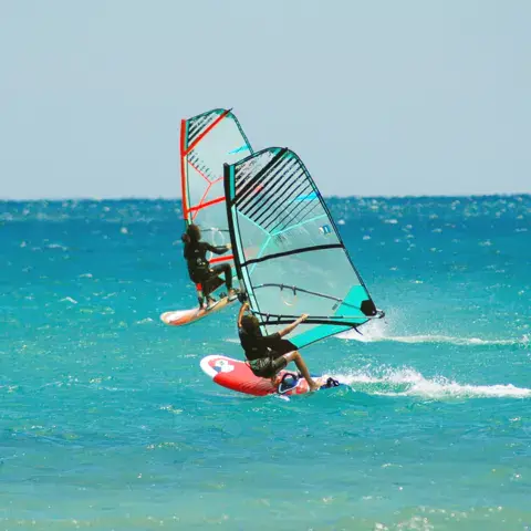 Deux windsurfeurs sur une eau turquoise
