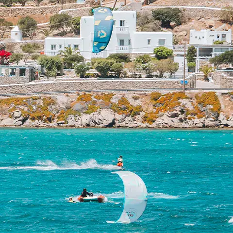 Kitesurfeur sur une eau turquoise devant la côte aux maisons blanches