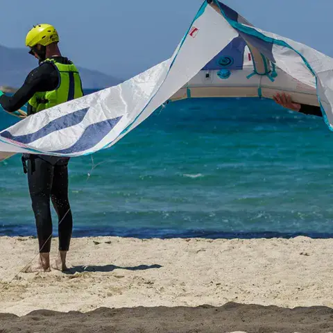 Moniteurs pliant une aile de kite sur la plage