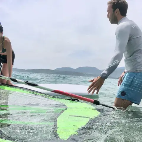 Instructeur et élève autour d'une planche à voile