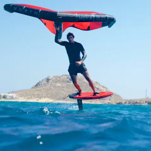 Rider de wingfoil au-dessus de l'eau, aile rouge