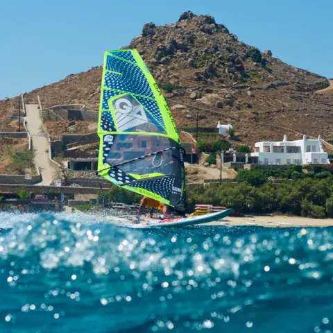 Windsurfeur devant une colline et des maisons en bord de mer