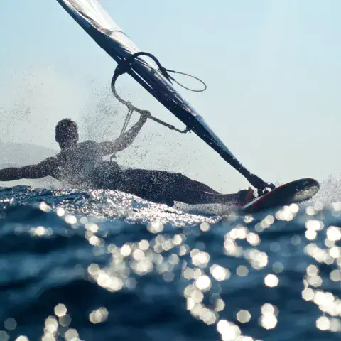 Windsurfeur plongeant dans l'eau scintillante