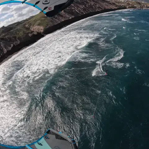 Vue de dessus d'une aile de kite au-dessus de la côte et des vagues