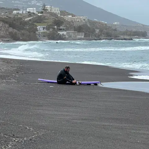 Plage de sable noir avec une planche de surf posée près du rivage