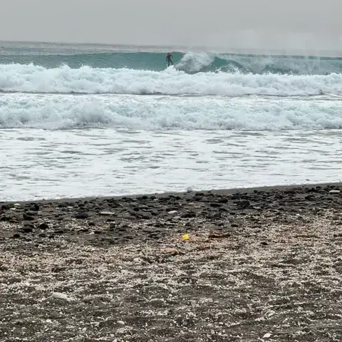 Vagues déferlant sur une plage de galets noirs