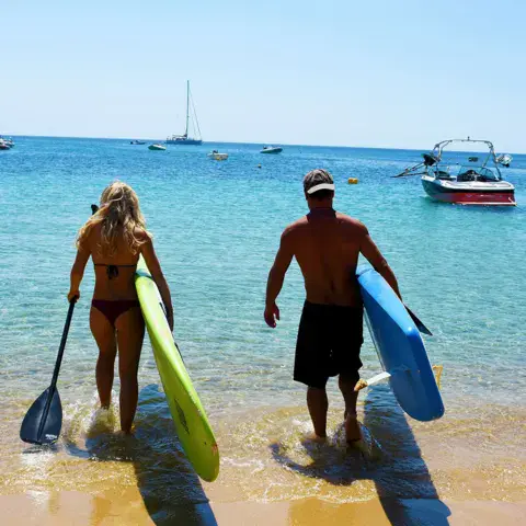 Deux personnes portant des planches de SUP vers l'eau