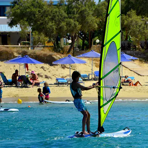 Windsurfeur sous une voile verte près de la plage