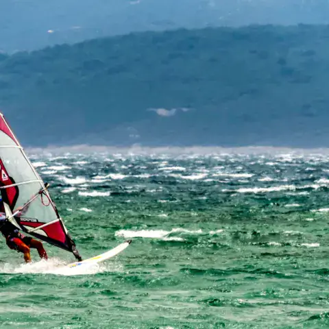 Windsurfeur sous voile rouge et blanche