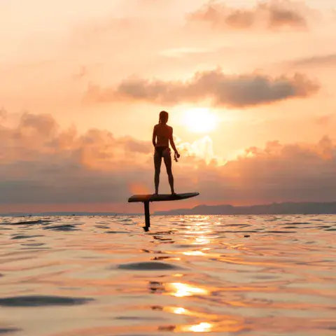 Rider sur une planche foil au coucher du soleil