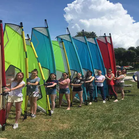 Groupe tenant des voiles de windsurf alignées
