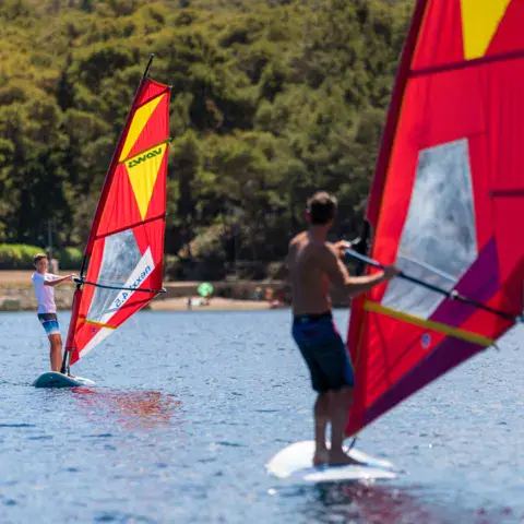 Cours de windsurf avec voiles rouges et jaunes
