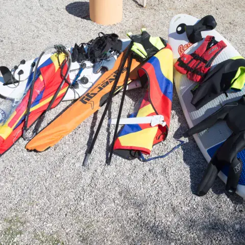 Matériel de windsurf et gilets posés sur la plage