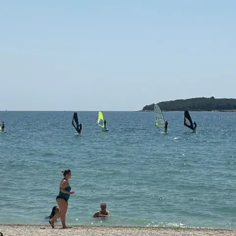 Windsurfeurs au large d'une plage de galets