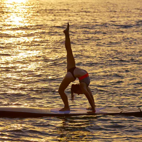Yoga sur une planche de paddle au coucher du soleil