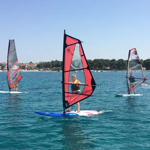 Windsurfeurs sur une mer calme, côte au loin