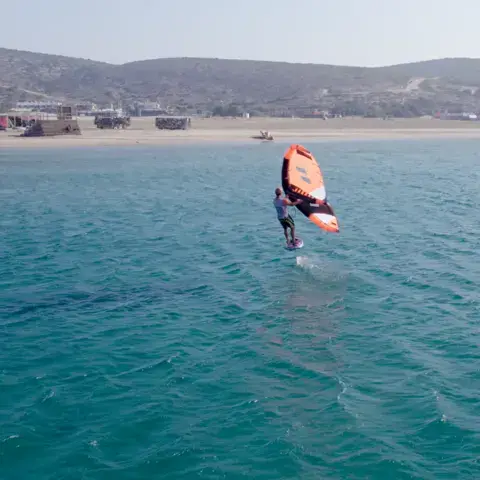 Rider de wing foil au-dessus de l'eau turquoise