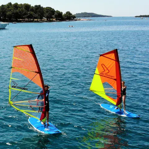 Deux planches à voile avec voiles orange et jaune