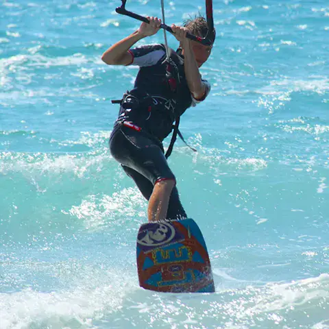 Kitesurfeur avec sa planche dans l'eau turquoise
